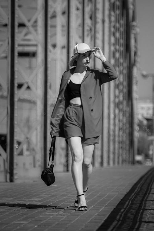 Grayscale Photo of a Stylish Woman Carrying Her Bag while Walking