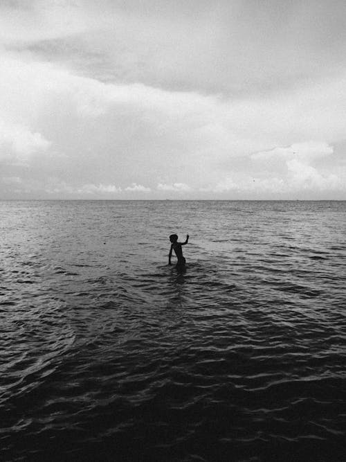 Monochrome Photo of a Person's Silhouette in the Sea