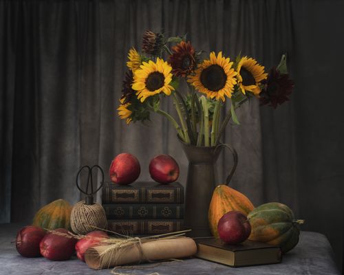 Free Artistic still life featuring sunflowers, books, and fruit, set on a vintage table. Stock Photo