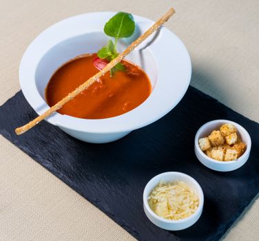 A delicious tomato soup served with parmesan and croutons, perfect for a gourmet meal.