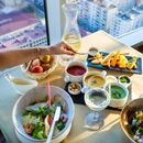 Person Holding Chopsticks in Front of Table With Food