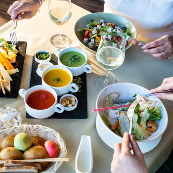 A colorful spread of fresh vegetarian dishes including salads and soups served at a dining table.