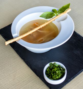 Elegant bowl of soup with breadstick and fresh basil garnish, perfect for culinary presentations.