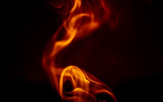 Dynamic orange flames create a striking abstract pattern on a dark background.