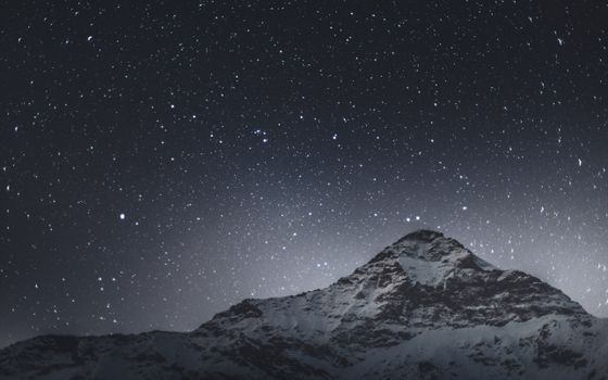 Stunning view of a starry night sky above a snow-covered mountain in Lombardy, Italy.