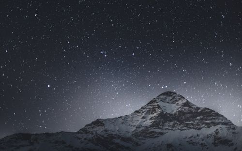 Free Stunning view of a starry night sky above a snow-covered mountain in Lombardy, Italy. Stock Photo