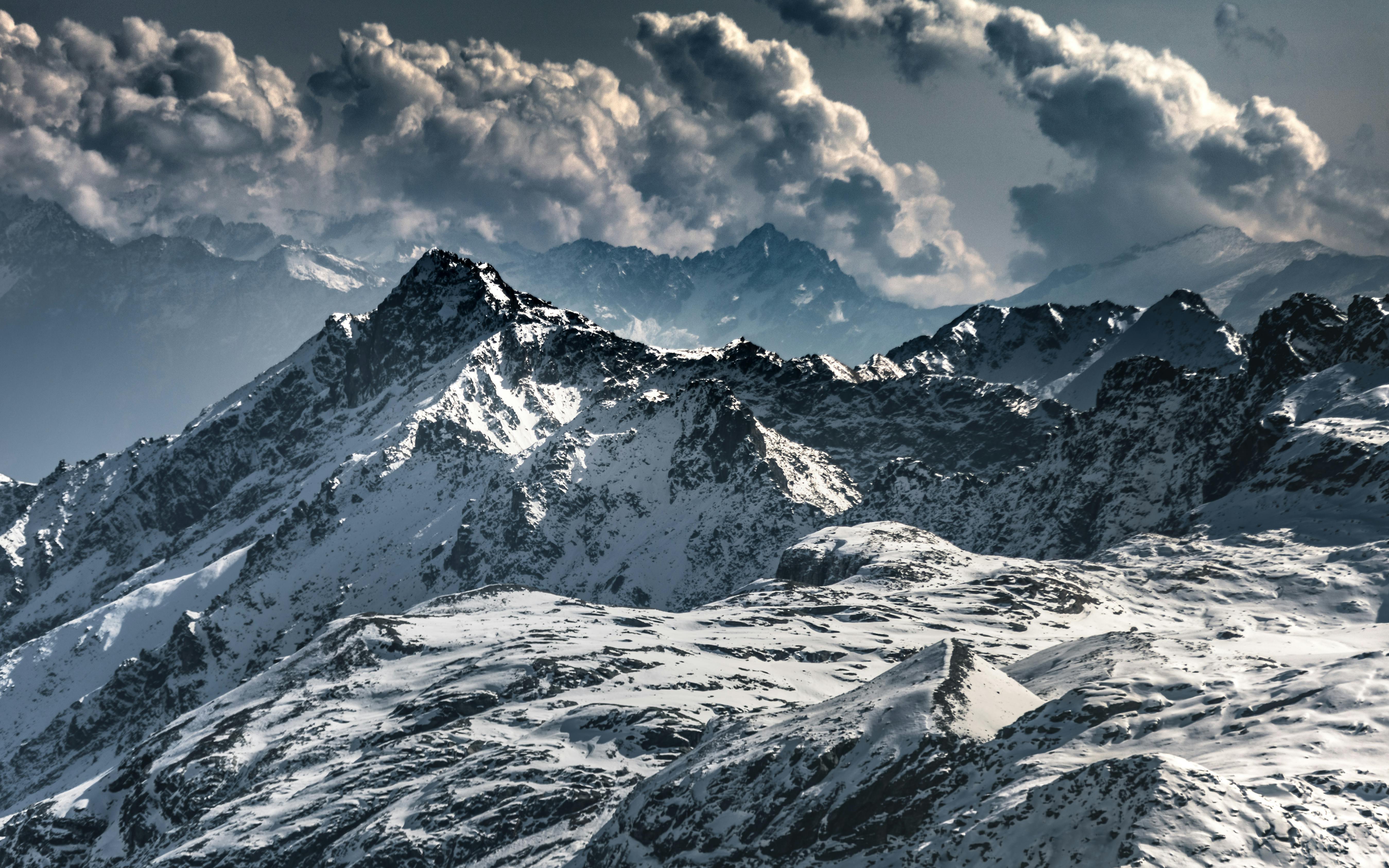 Majestic snow-covered mountains under dramatic clouds in Lombardy, Italy.