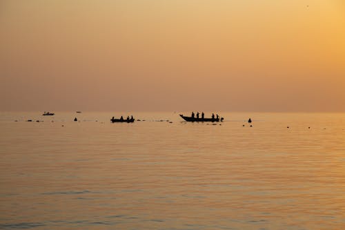 A Silhouette of Fishermen on Boats
