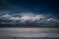 Panoramic view of Chaka Salt Lake with dramatic clouds and distant mountains in Qinghai, China, during twilight.