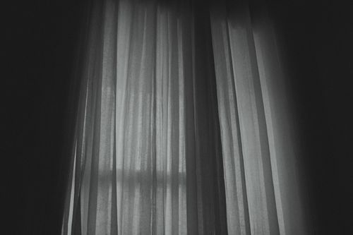 Free A moody black and white image of translucent curtains casting shadows indoors. Stock Photo