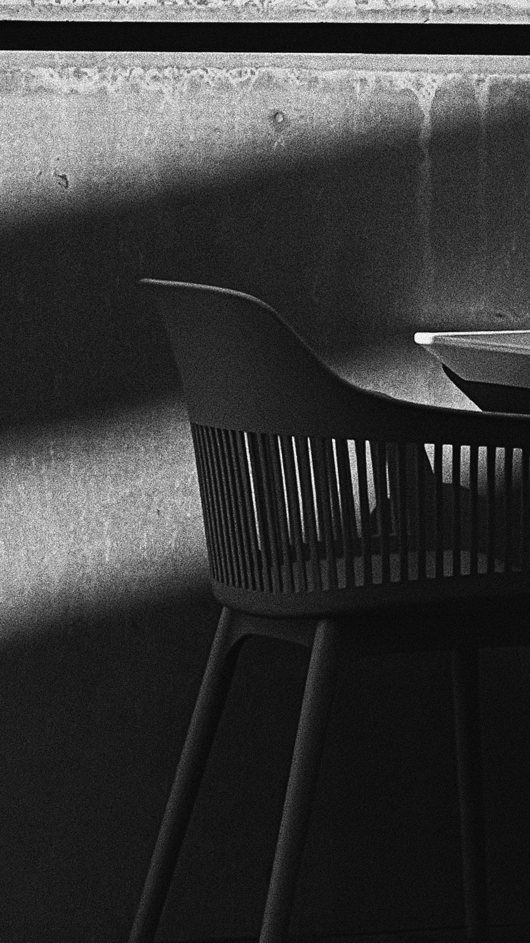 Black chair casting shadows on a concrete wall showcasing minimalist design and light play.
