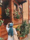 A Person Wearing Blue Hijab Looking at the Potted Plants Outside the House