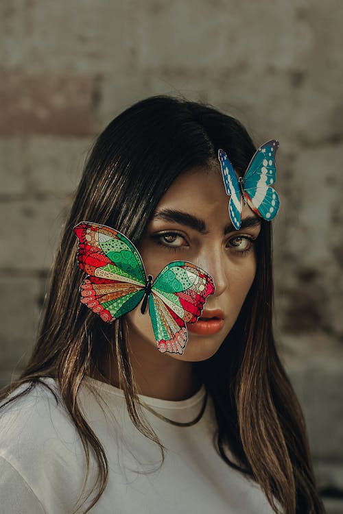 Beautiful Woman Looking at the Camera with Butterflies on Her Face