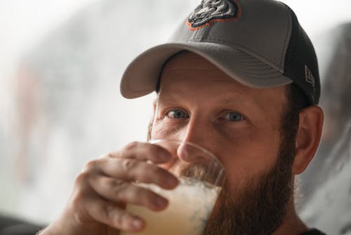Free Selective Focus Photo of a Man in a Gray Cap Drinking from a Glass Stock Photo