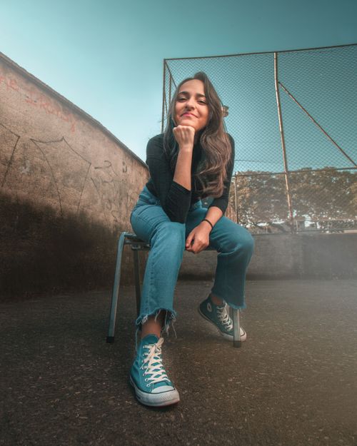 Free Confident young woman poses sitting outdoors on a chair with a thoughtful expression. Stock Photo