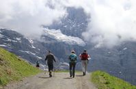 People Walking on Gray Pathway Near Mountain Covered With Snow