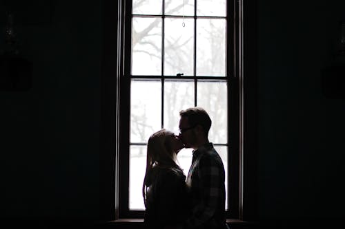 Free Man and Woman Kissing Beside Window Stock Photo