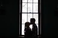 一对情侣在背光的大窗前接吻，形成浪漫的剪影