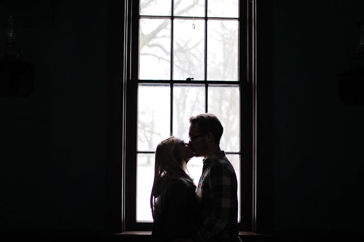 Man And Woman Kissing Beside Window