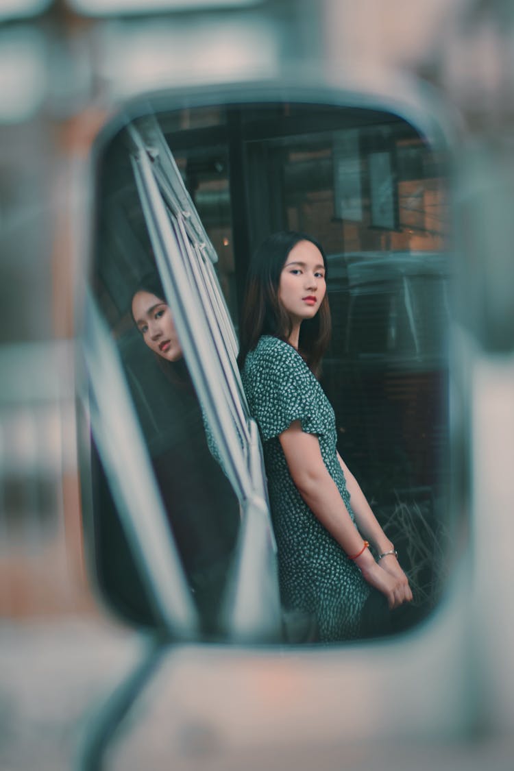 Photo Of A Woman In A Green Dress Looking At A Side Mirror Of A Car