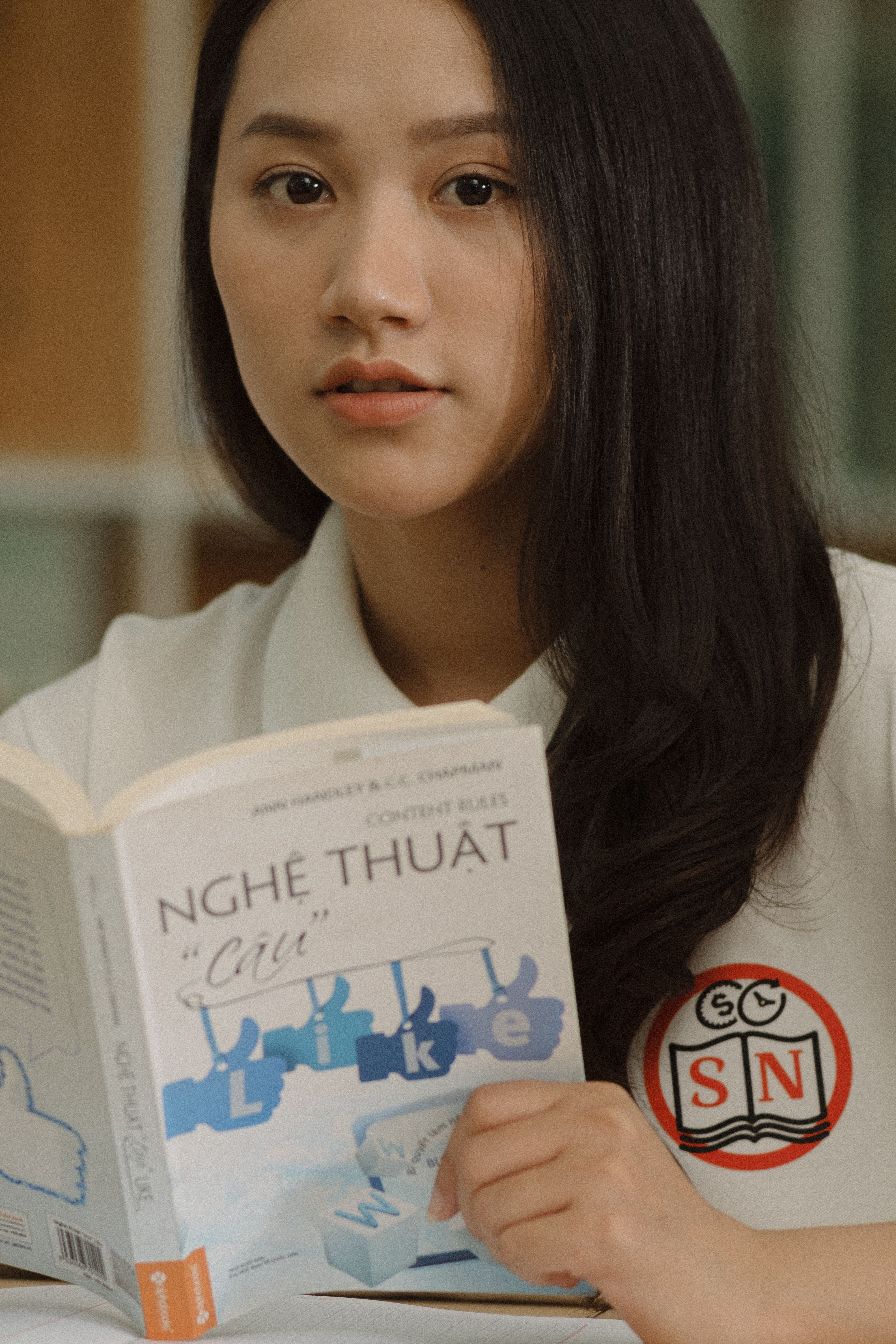 Young woman holds a book in a calm indoor setting, embodying learning.