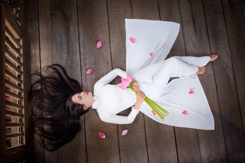 Free Woman in White Dress Lying on Wooden Floor Stock Photo