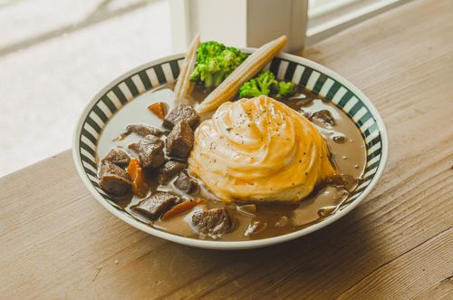 Free Savor the rich flavors of a beef stew served with creamy mashed potatoes and fresh vegetables in a cozy setting. Stock Photo