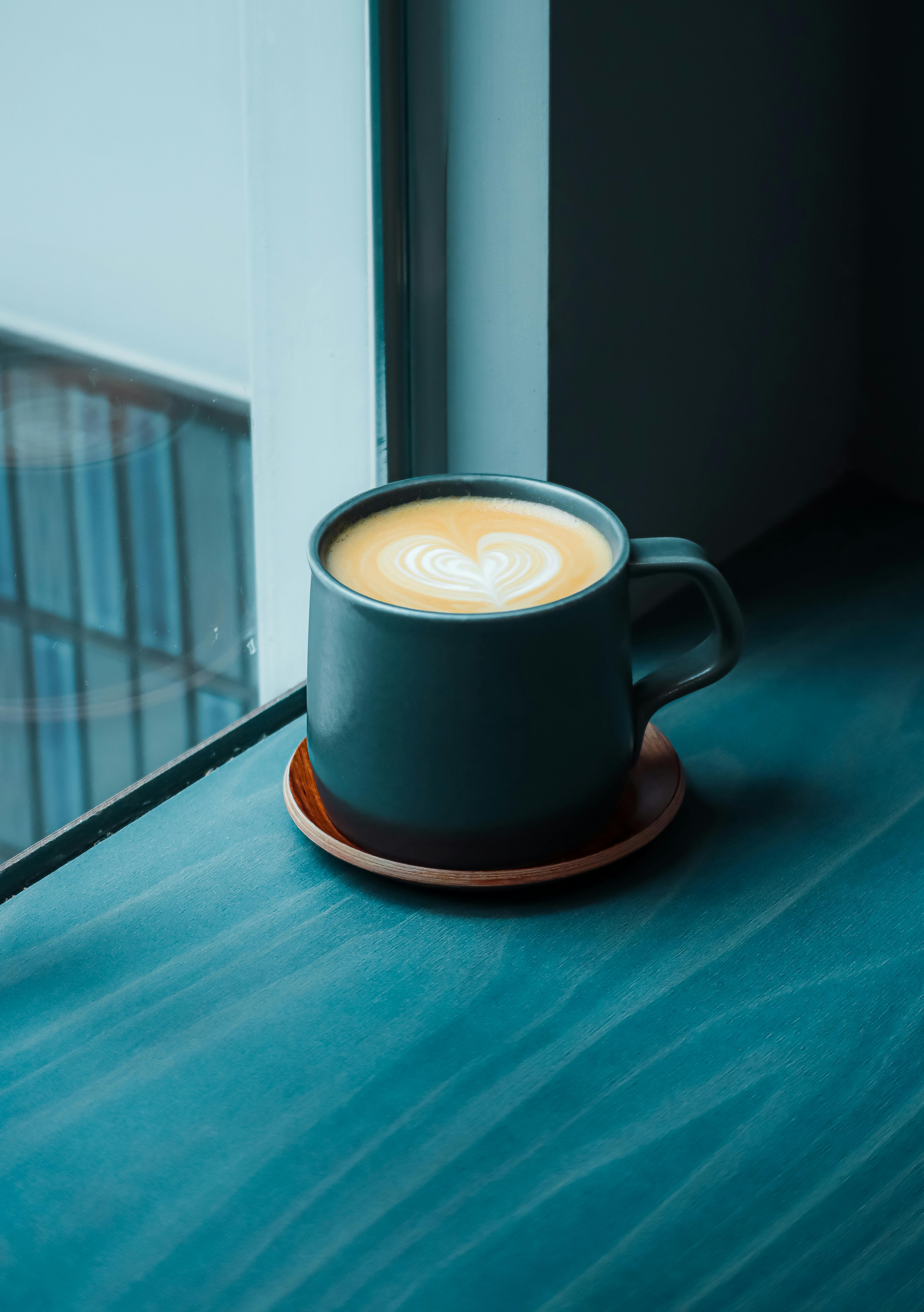 Close-up of a heart-shaped latte art in a cup by the window.
