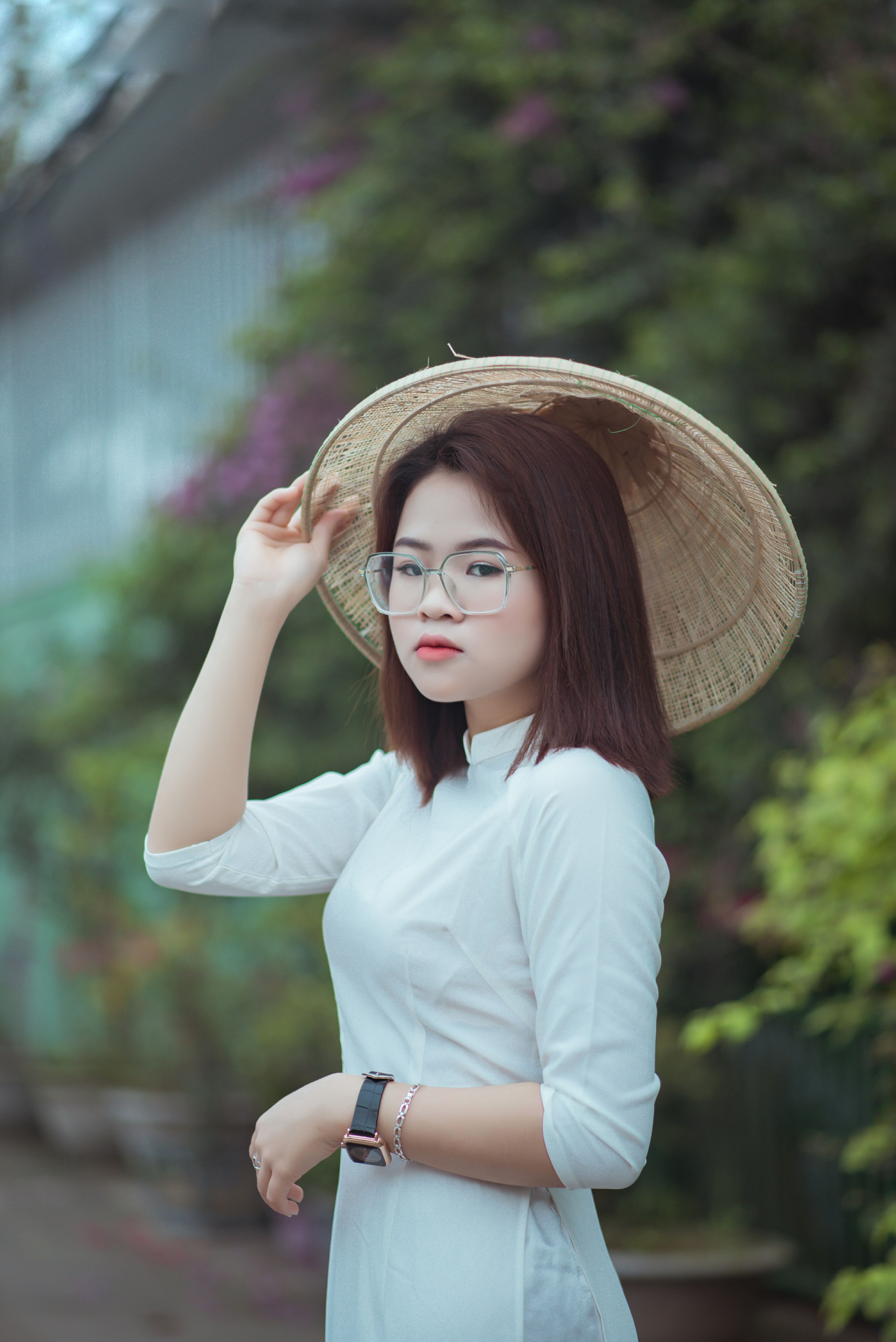 Portrait of a young woman in traditional Asian clothing wearing an Asian conical hat outdoors.