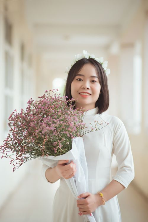 Free Bride in white dress holding bouquet, smiling elegant portrait shot in soft light. Stock Photo