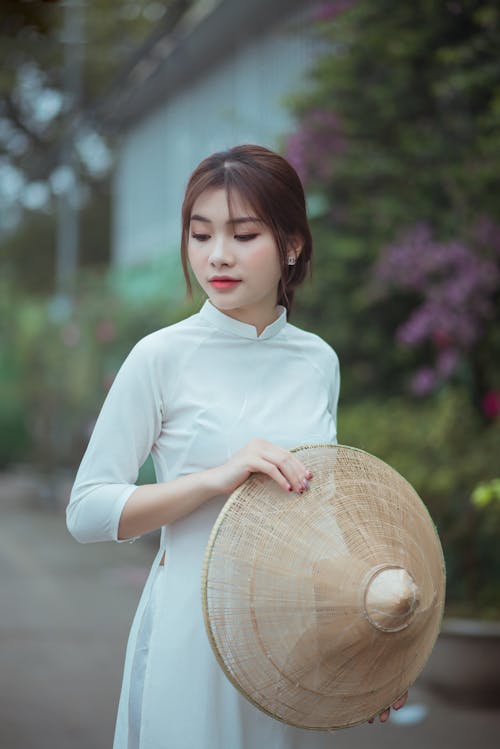 Free A Woman in white Dress Holding an Asian Conical Hat Stock Photo