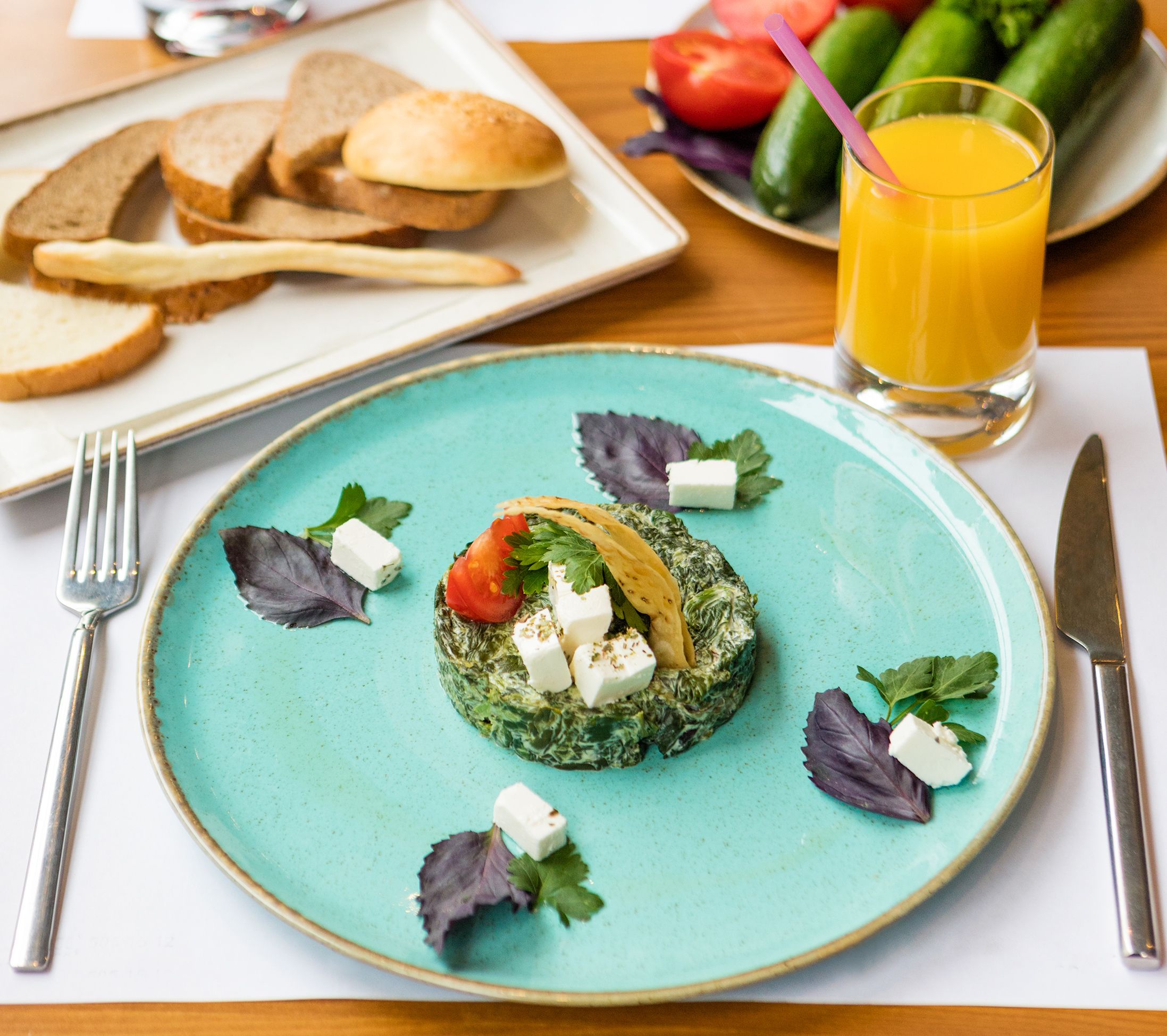 Delicious Mediterranean salad with fresh herbs, feta, and tomato on a turquoise plate.