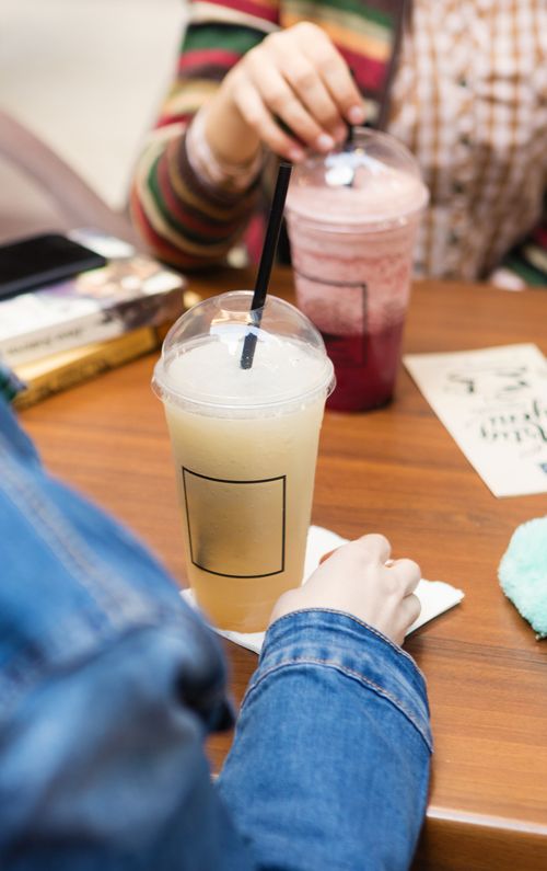 Free Two people enjoying refreshing fruit juices at a cafe, captured indoors on a wooden table. Stock Photo