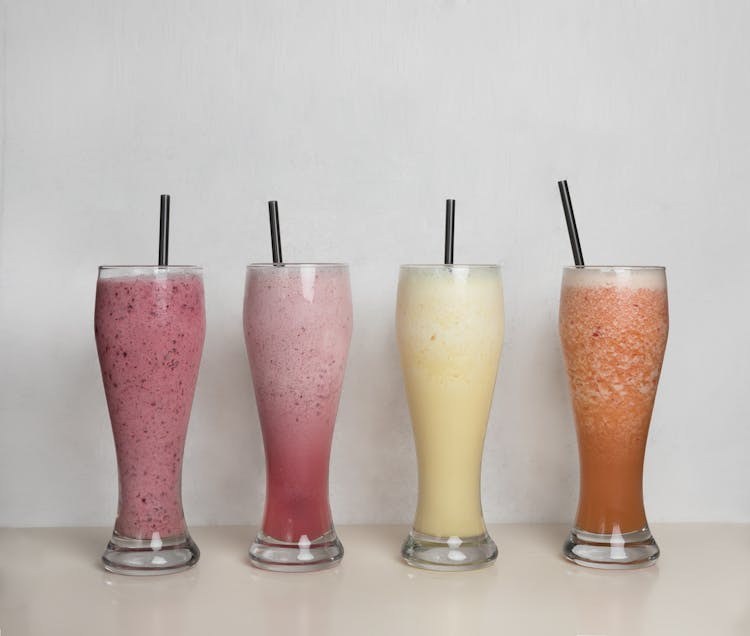 Assorted Flavor Of Fruit Shakes On Tall Glasses