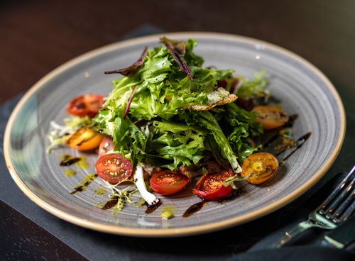 Free Delicious and healthy vegetable salad with fresh lettuce and cherry tomatoes, elegantly presented on a ceramic plate. Stock Photo