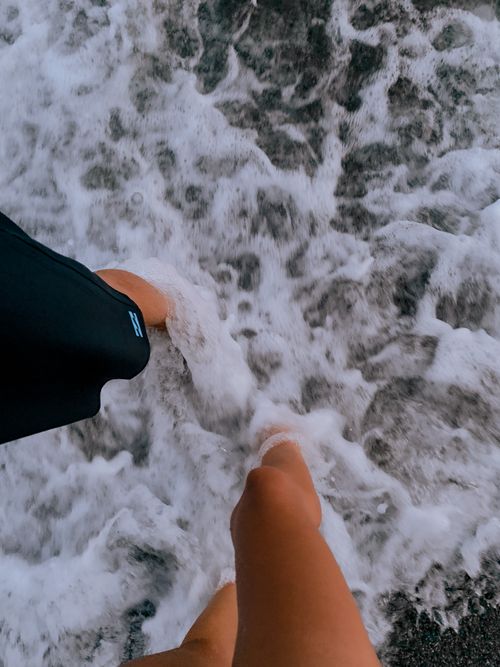Free Two people standing in seafoam at the beach from above, capturing a relaxed summer vibe. Stock Photo