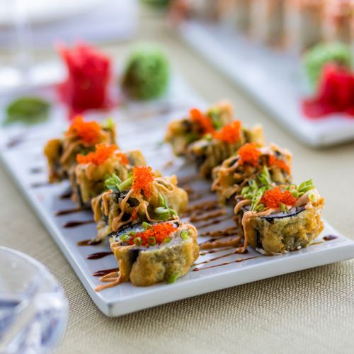 Free Close-up of gourmet sushi rolls topped with caviar and vibrant garnishes, elegantly plated. Stock Photo
