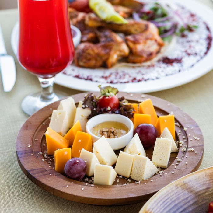 Platter of assorted cheeses and grapes served with a chilled drink, photo by Farhad Ibrahimzade on Pexels