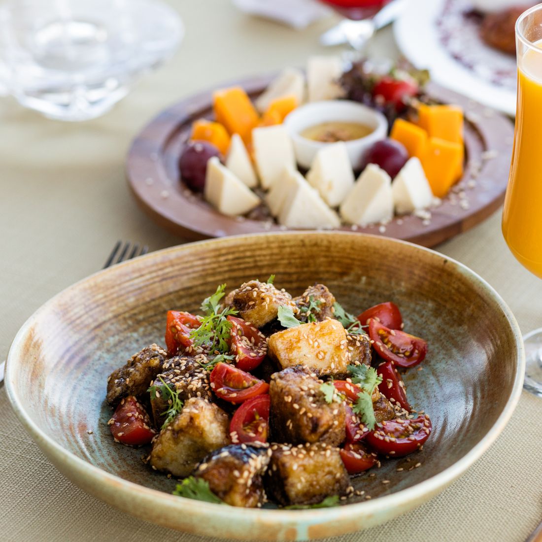 Mouth-watering vegetarian meal with fresh vegetables and cheese platter in a cozy setting.
