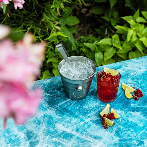 Clear Drinking Glass With Red Liquid on Blue and Pink Floral Table Cloth