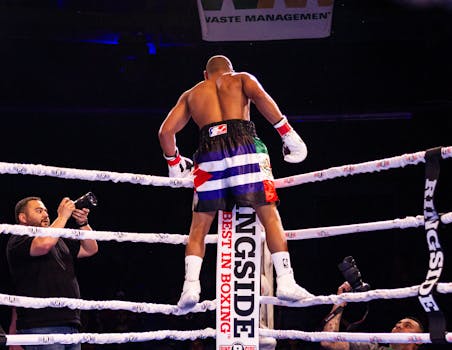 Boxer celebrates victory in the ring, captured with photographers in action.