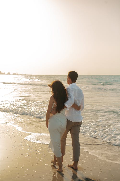 Free Back View of a Romantic Couple Walking on the Beach Stock Photo