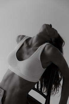 Artistic black and white portrait of a woman in a sports bra, showcasing elegance and serenity.