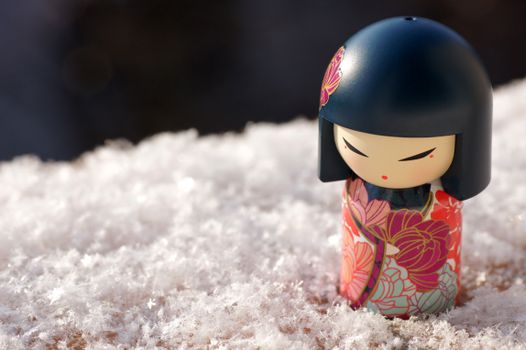 Close-up of a Kimmidoll figurine on snow-covered surface, exuding winter charm.