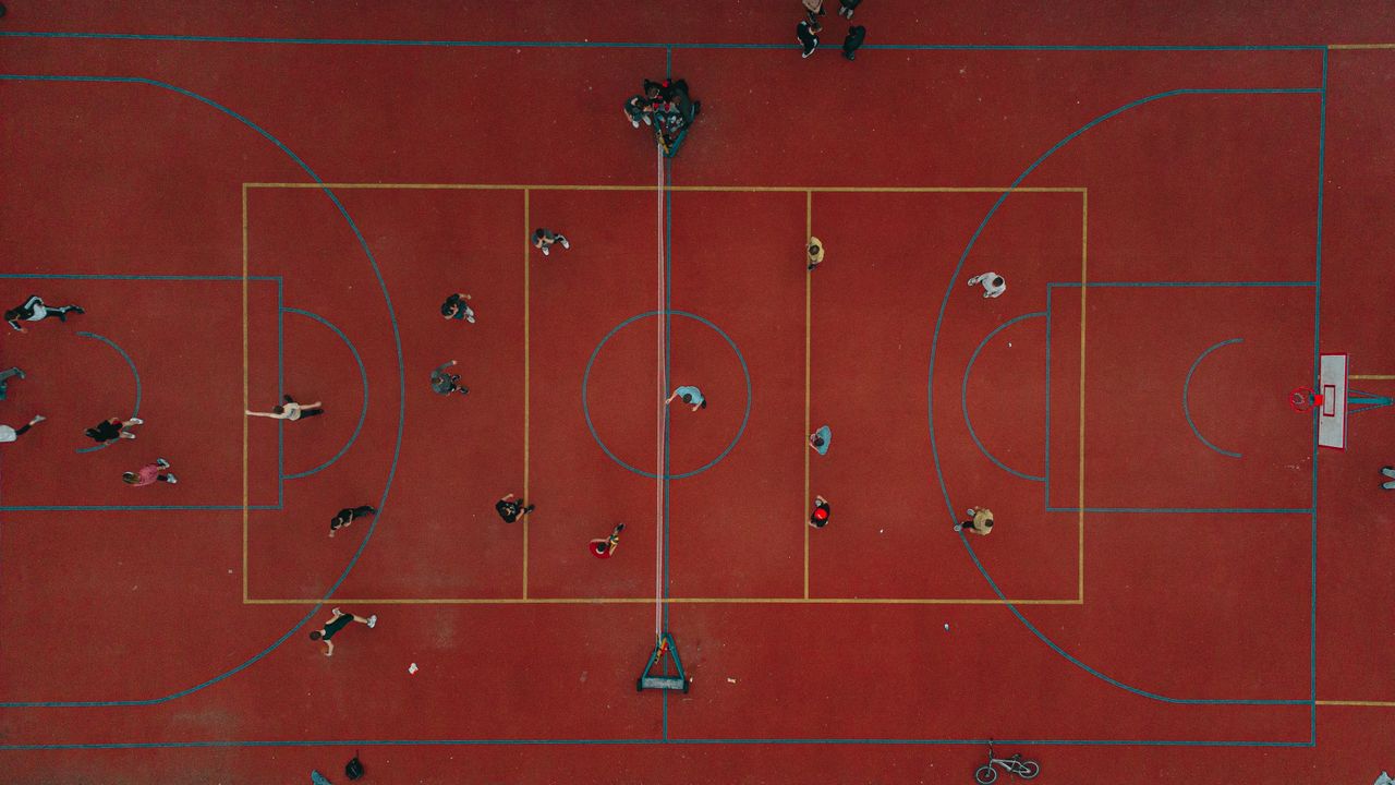 dynamic aerial perspective of people playing on a vibrant red basketba