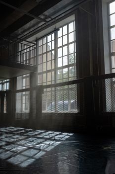Atmospheric shot of sunlight casting shadows through large industrial windows, creating a dramatic interior scene.