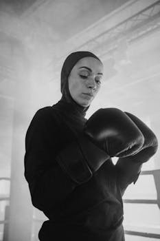 Empowering black and white portrait of a determined female boxer training indoors.