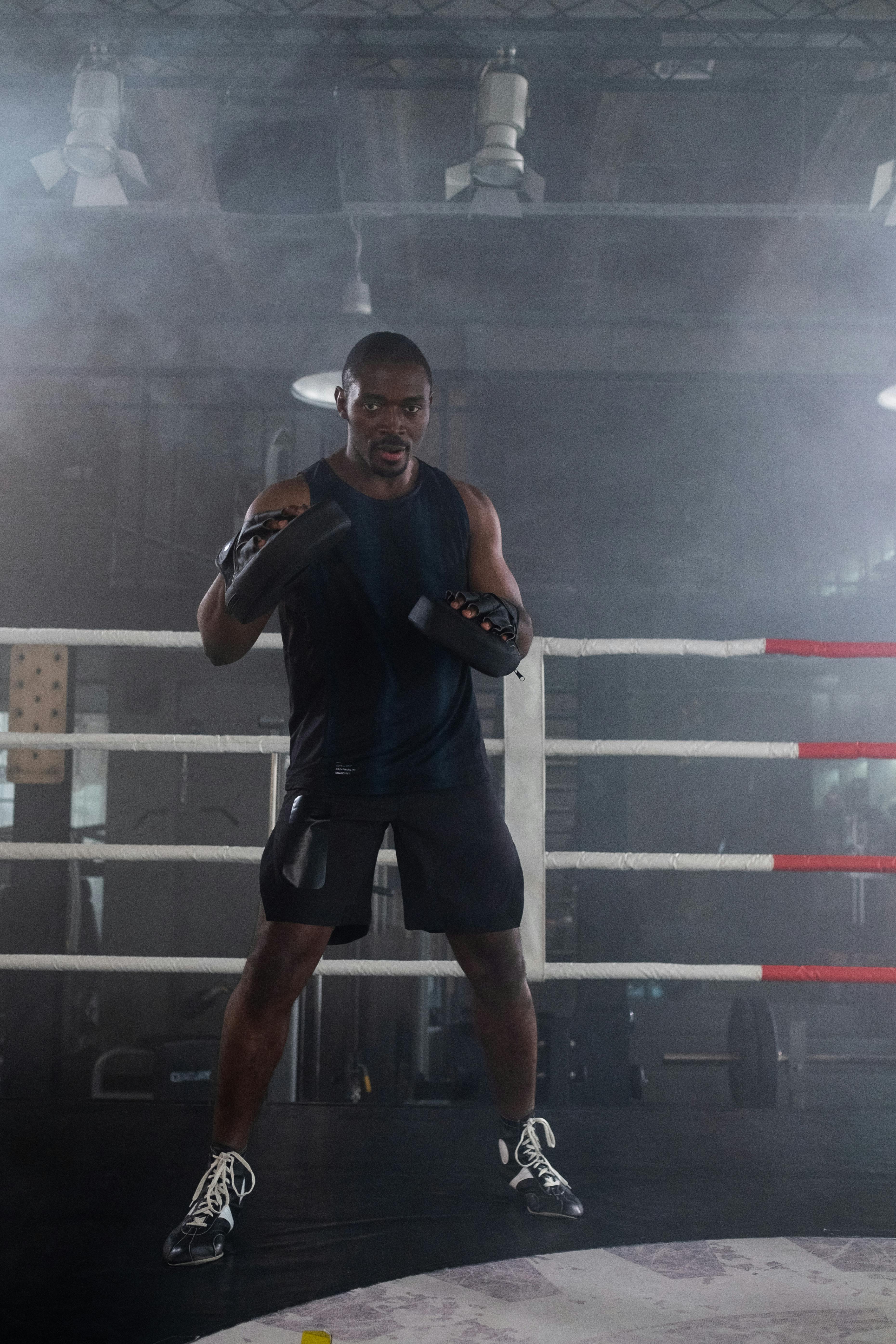 man with boxing pads standing inside a boxing ring