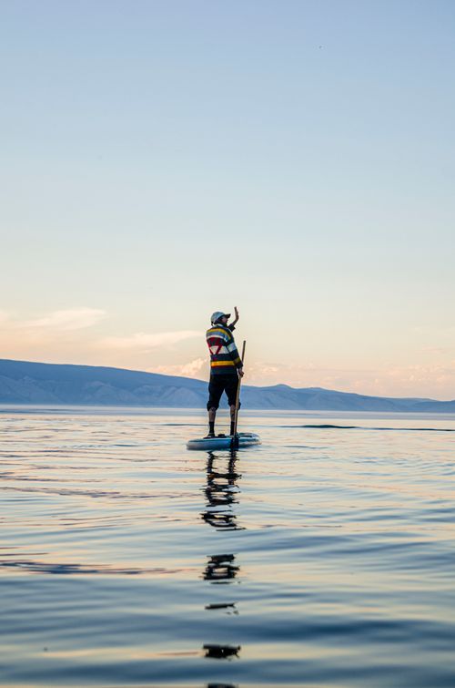 Free A person paddleboarding on a serene lake during sunset, showcasing outdoor adventure and tranquility. Stock Photo