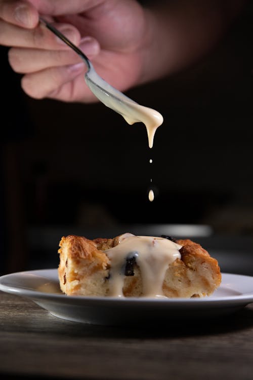 Person Holding a Spoon with Creamy Sauce